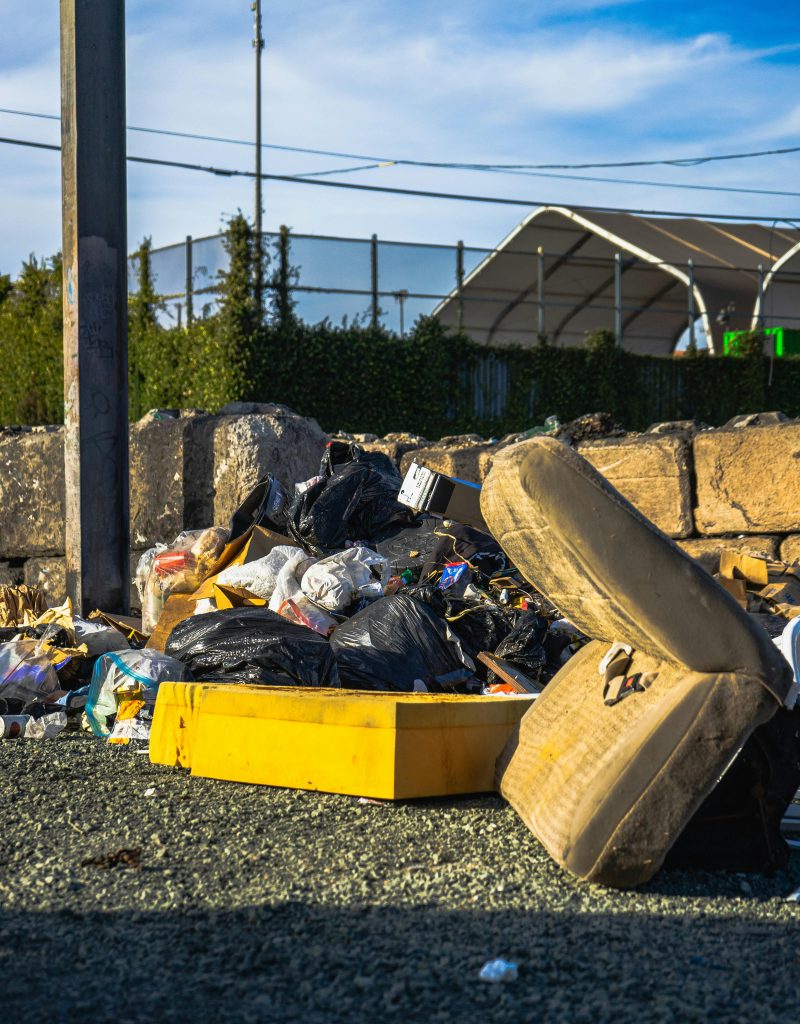 Outdoor scene of a garbage pile including a discarded mattress and various waste materials.